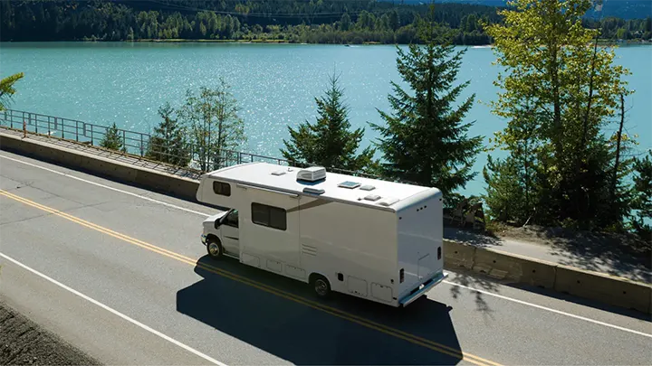 featured image depicting an RV riding on a road next to a body of water