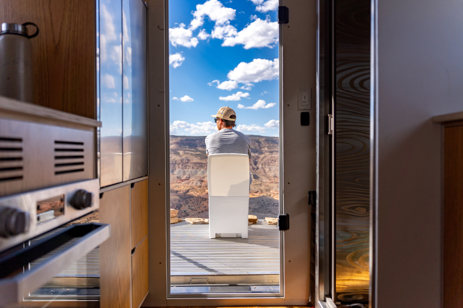 Man sitting on cuddy composting toilet, looking out into a canyon