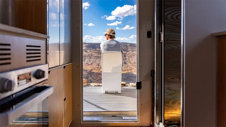 Man sitting on cuddy composting toilet, looking out into a canyon