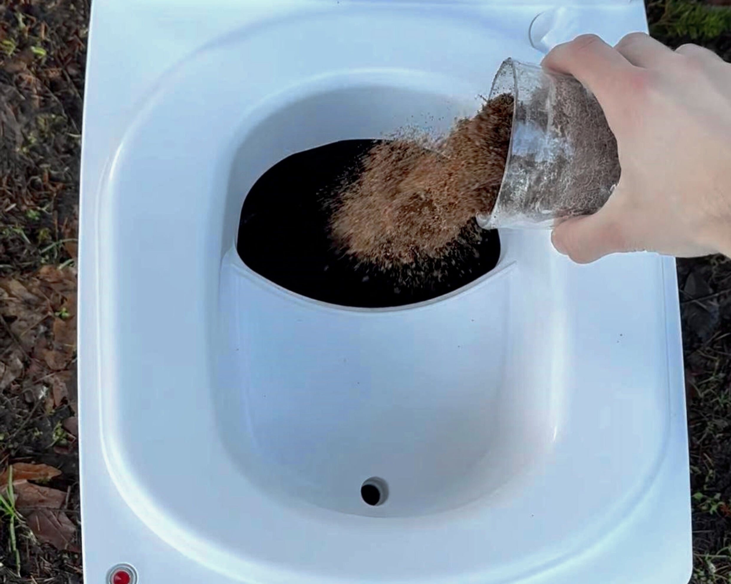Cuddy Lite composting toilet with a layer of coco coir being poured in