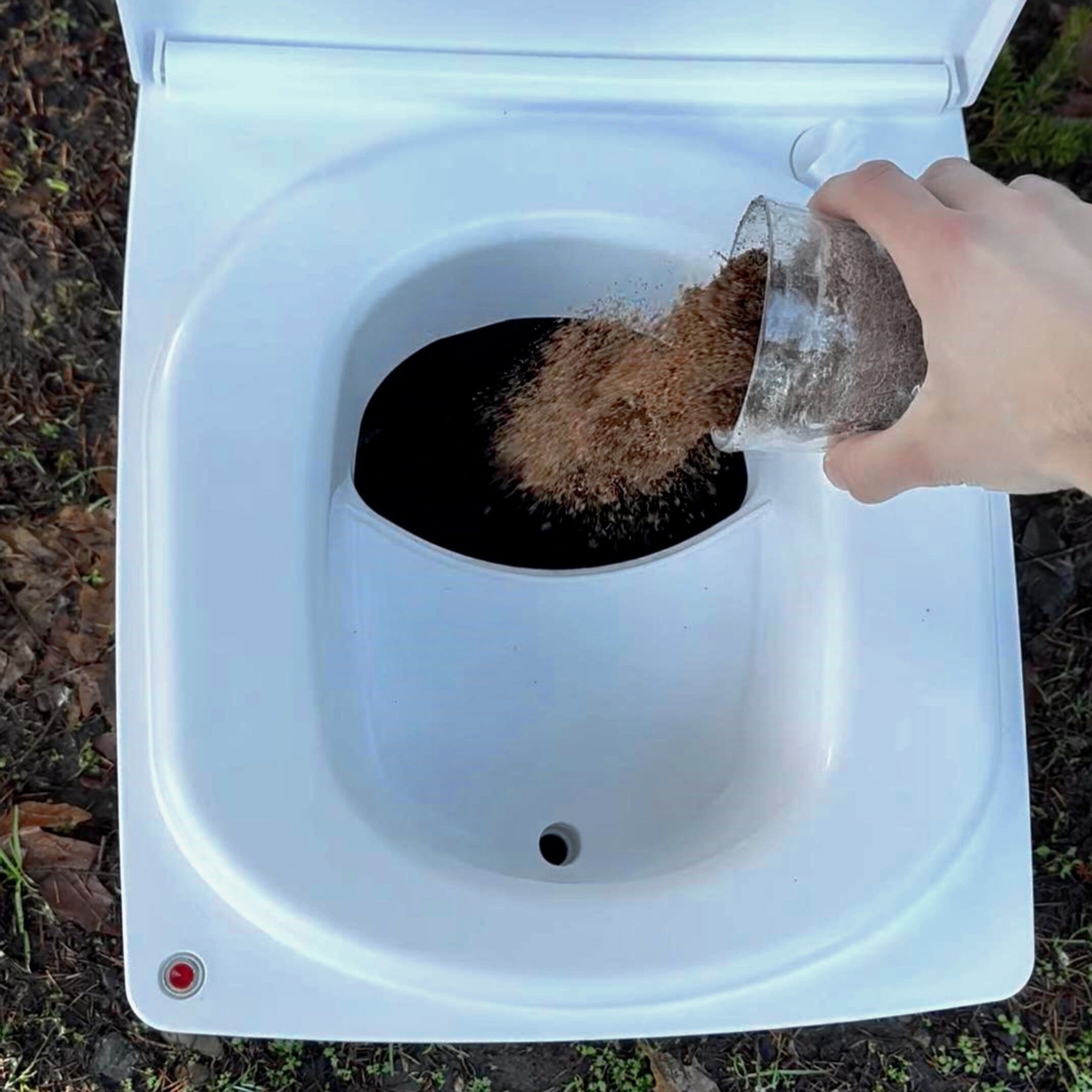 Cuddy Lite composting toilet with a layer of coco coir being poured in