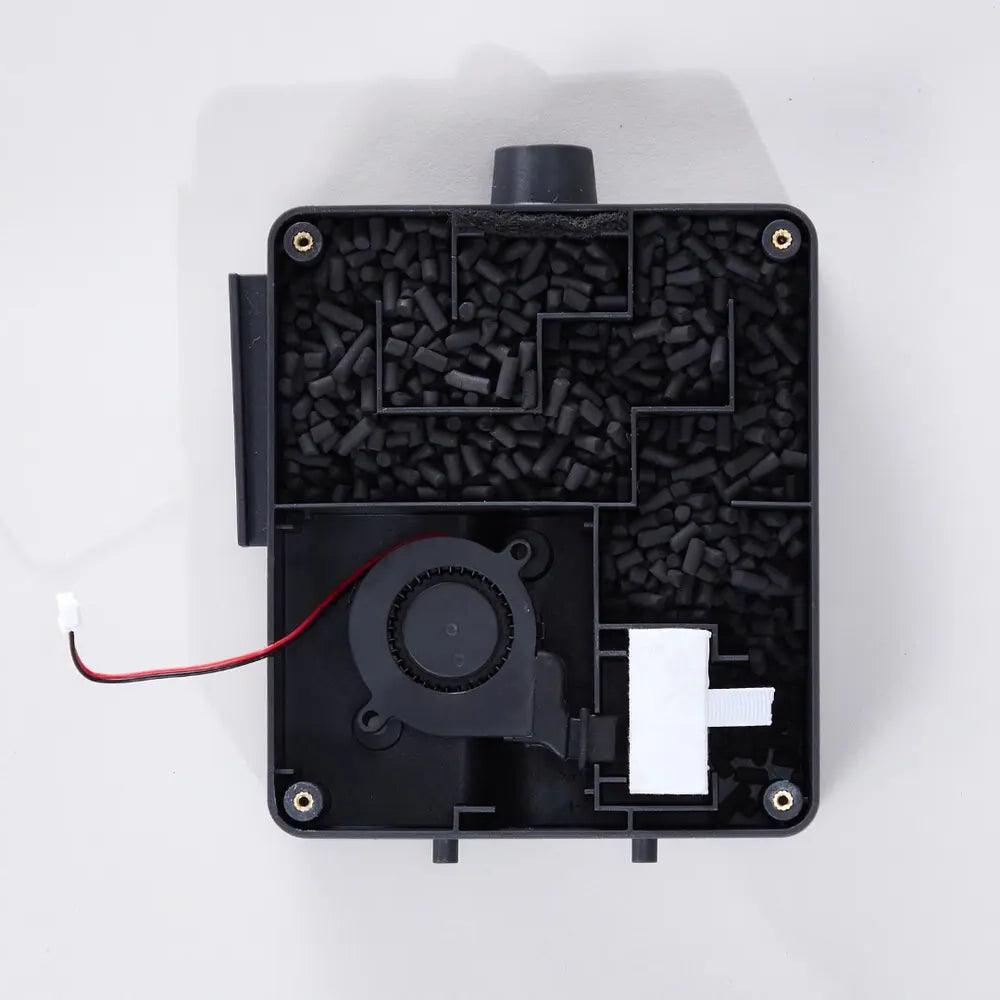 Inside view of the external carbon filter. Black electronic component with carbon pellets, fan and wires on a white background