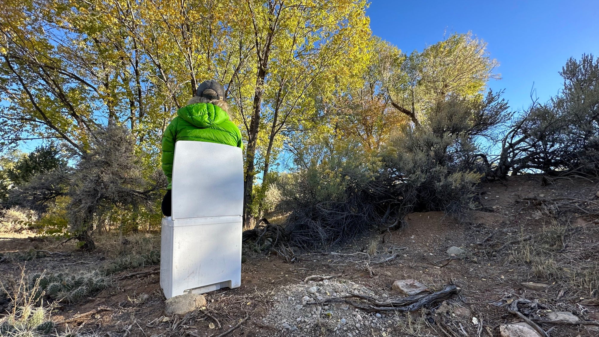 Woman sitting on a portable compost toilet off grid.