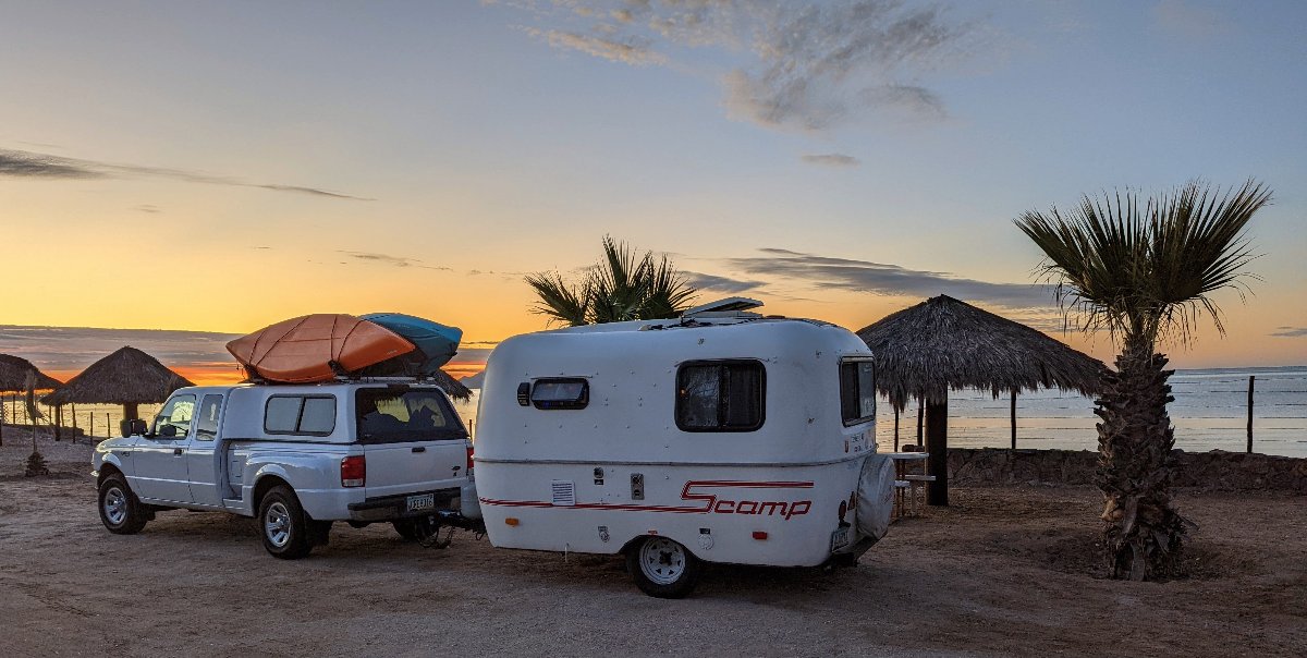 scamp-camper-pulled-by-truck-with-kayaks-at-beach.jpg