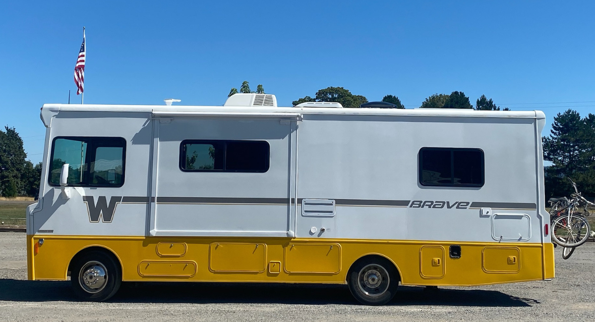 White and yellow RV with 'Brave' branding on a clear day.